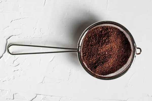 Ground coffee in a strainer, Freepik.